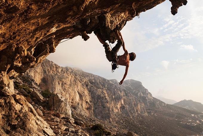 在险峻的悬崖上攀岩的男人高清图片
